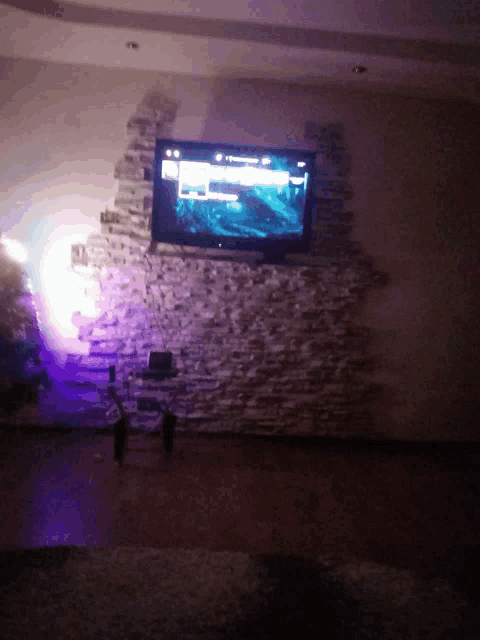 a flat screen tv is mounted on a stone wall in a dark room