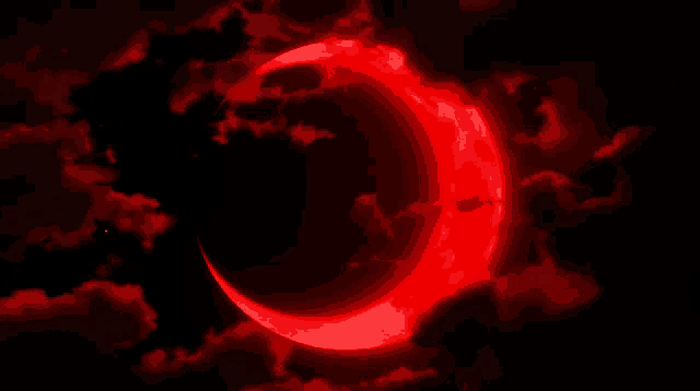 a red crescent moon in a dark sky with clouds