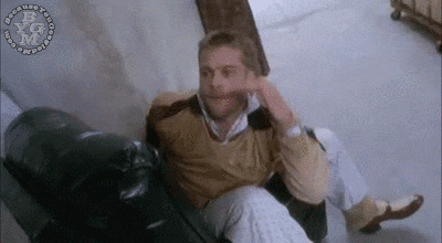 a man is sitting on a couch with his legs crossed and his hand on his chin .