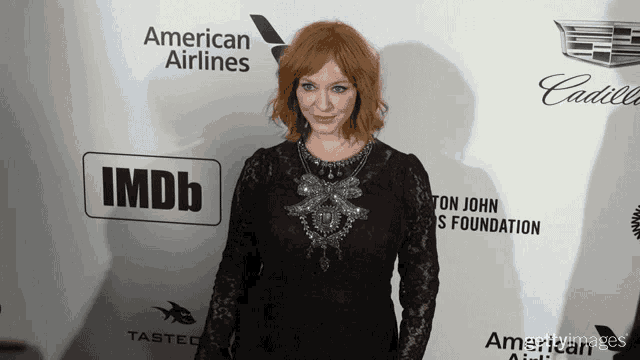 a woman stands on a red carpet sponsored by american airlines
