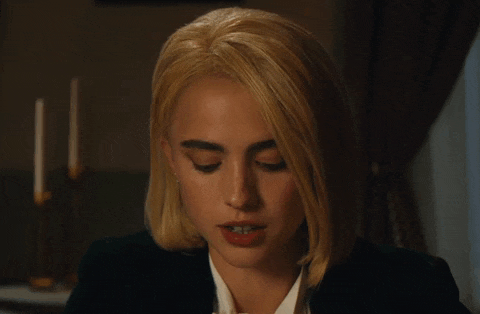 a woman with blonde hair and blue eyes is wearing a black suit