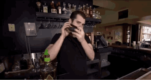 a man in a black shirt holds a shaker in his hand