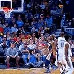 a group of people are watching a basketball game being played on a court .