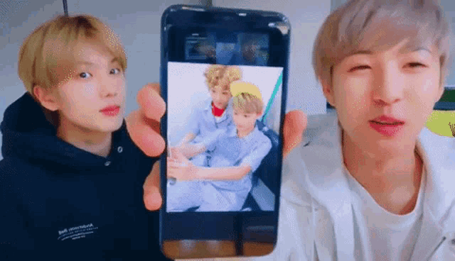 a man is holding a cell phone with a picture of a couple on it .