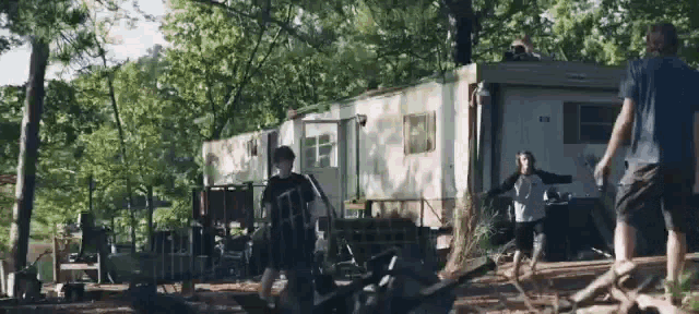 a group of people standing in front of a trailer in a forest .