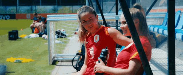two female soccer players are sitting next to each other on a bench