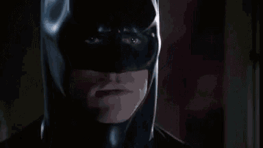a close up of a man wearing a batman mask and looking at the camera .