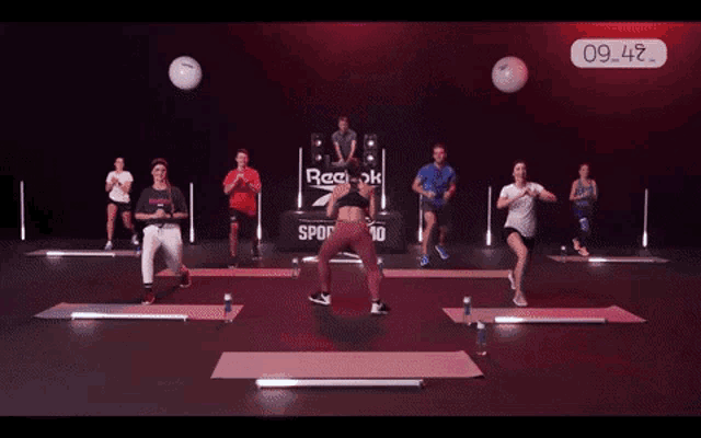 a group of people doing exercises in front of a reebok sign