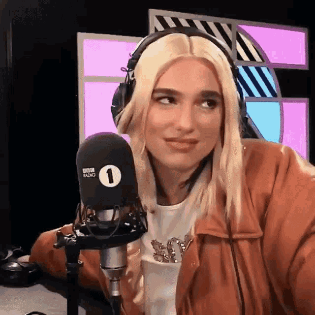 a woman wearing headphones is sitting in front of a microphone and making a funny face .