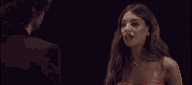 a woman in a red dress talks to a man in a suit