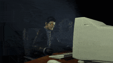 a man in a suit and tie is sitting in front of a computer screen