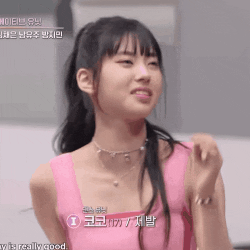a girl is wearing a pink tank top and a necklace and says that she is really good