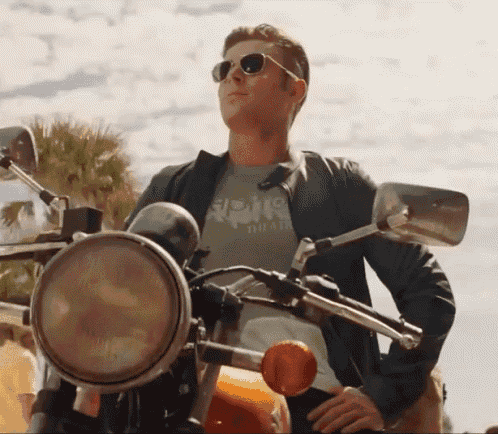 a man is sitting on a motorcycle wearing sunglasses and a shirt that says aloha