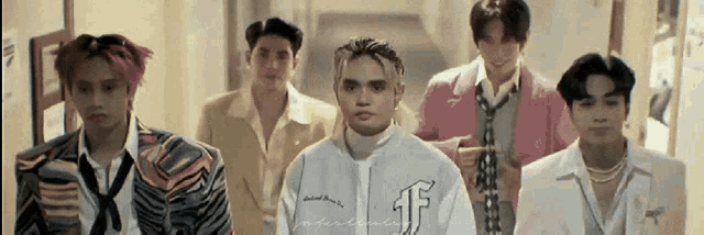 a group of men are standing next to each other in a hallway .