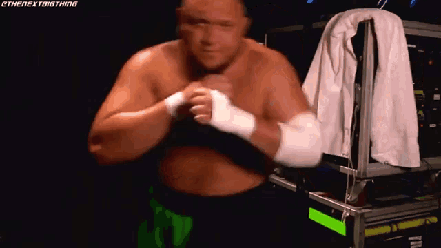 a shirtless wrestler with a white towel hanging on a rack with the hashtag #thenextbigthing