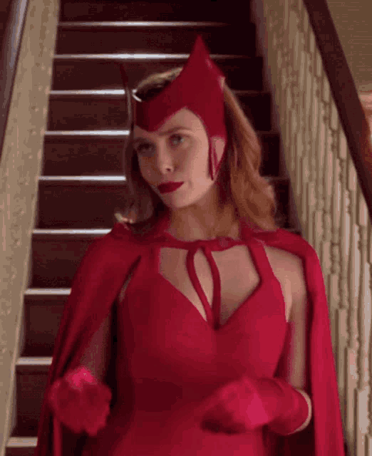 a woman in a red cape and gloves is standing on a set of stairs