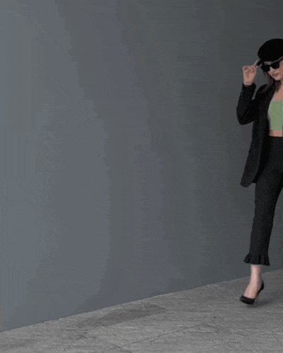 a woman wearing a hat and sunglasses is carrying a black christian dior bag