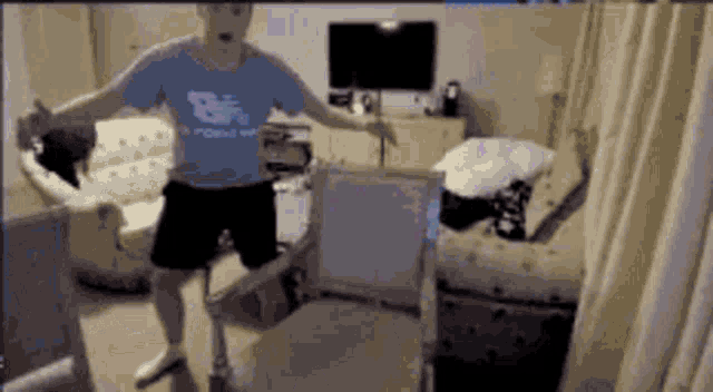 a man in a blue shirt that says bf on it is dancing in a living room