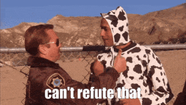 a man in a cow costume talks to a man in a sheriff 's uniform