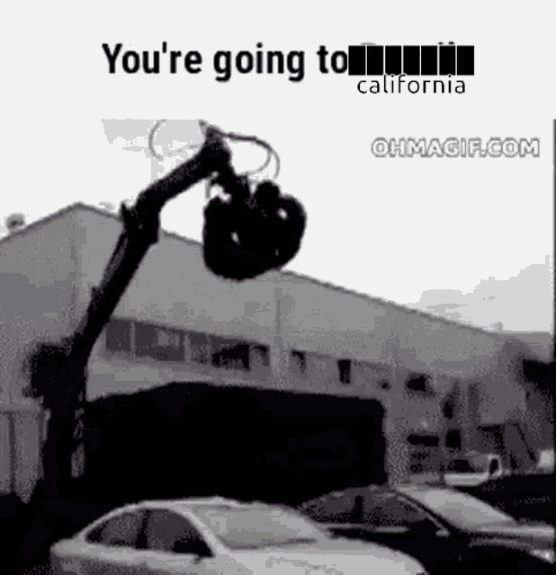 a car is being lifted by a crane in front of a building .