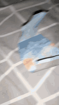 a blurred image of a person walking on a tiled floor with a blue item in the foreground