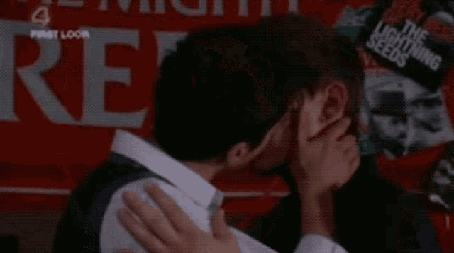 a man kissing another man in front of a sign that says " the lightning seeds "