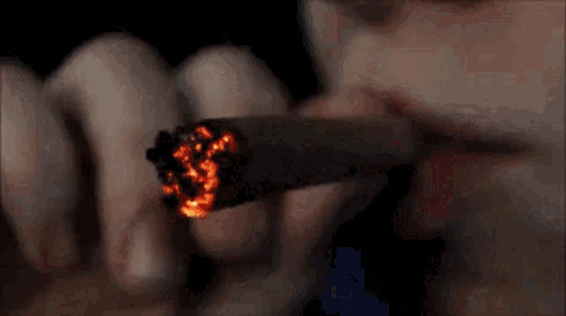 a close up of a person smoking a cigarette with a lighter .