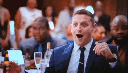 a man in a suit and tie is making a funny face at a party