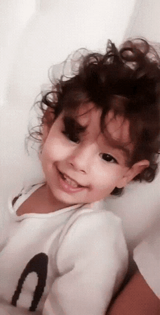 a little girl wearing a white shirt with the letter a on it smiles for the camera