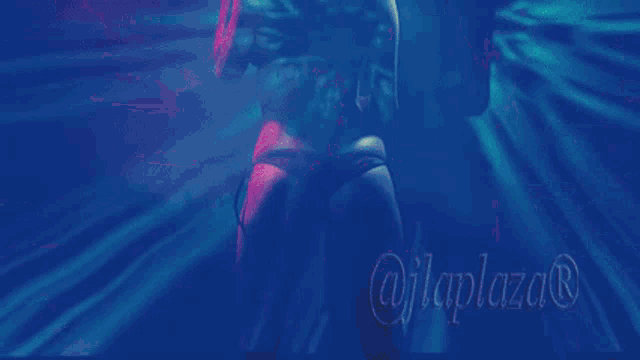 a woman is dancing in a room with purple and blue lights .