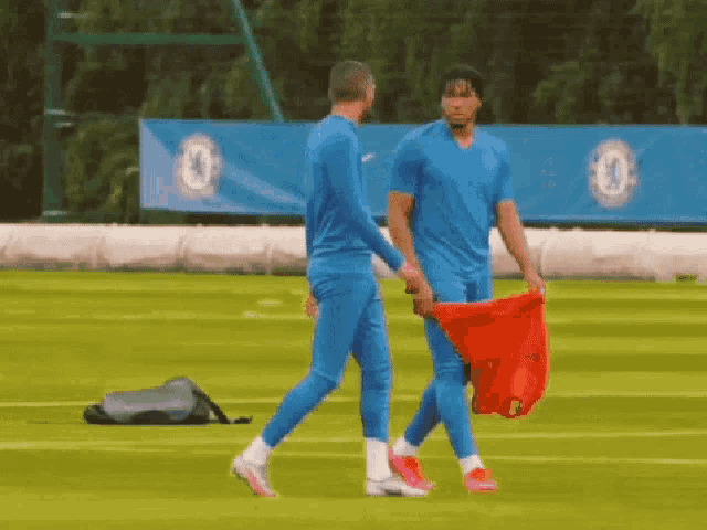 two soccer players are walking on a field and one of them is holding a red shirt