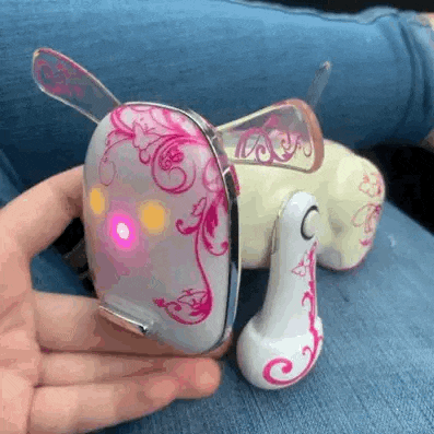 a person is holding a toy dog with a pink light on the back .