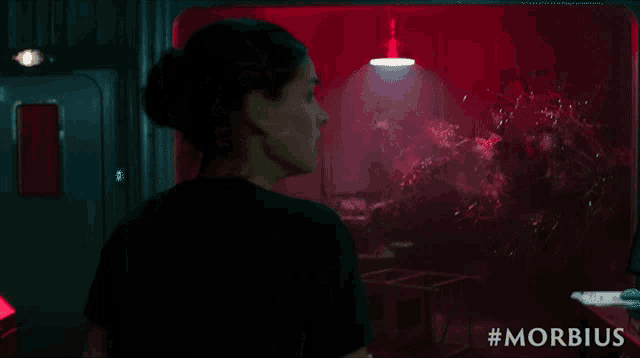 a woman in a black shirt is standing in a dark room with #morbidus on the bottom