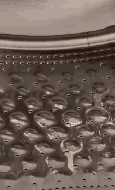 a close up of the inside of a washing machine drum with holes in it .