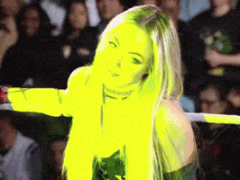 a woman is standing in a wrestling ring with her arms outstretched in front of a crowd