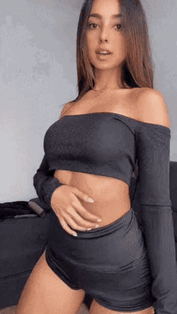 a woman in a black off the shoulder crop top and shorts