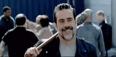 a man with a beard is holding a baseball bat over his shoulder .