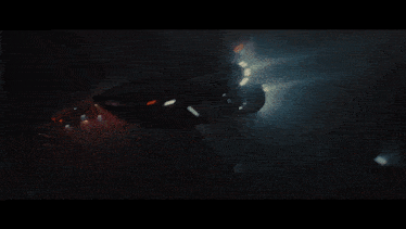 a car is flying through the air at night with the lights on
