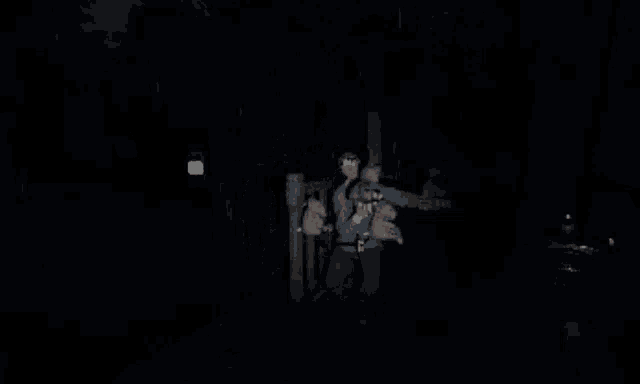 a man in a blue shirt is standing in a dark room