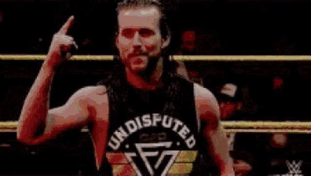 a man in a wrestling ring is wearing a black tank top with the word boom on it .