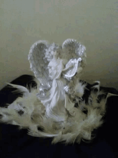 a statue of a white angel playing a harp surrounded by white feathers