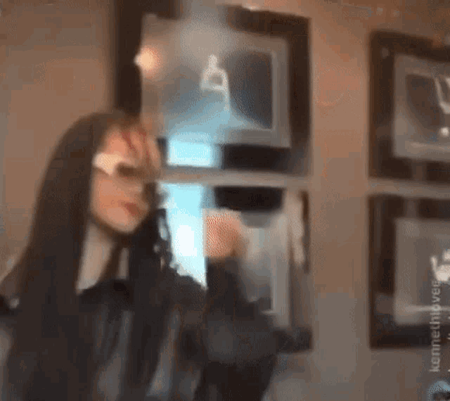 a woman wearing sunglasses and a black jacket is standing in front of a wall of pictures .