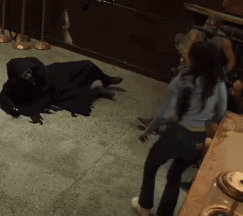 a woman is standing next to a grim reaper on the floor in a dark room .