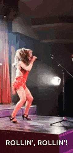 a woman in a red dress is singing into a microphone on stage .