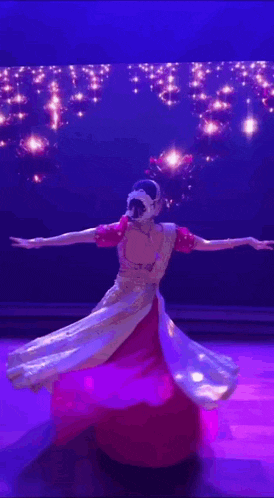 a woman in a red and white dress is dancing on a stage in front of a blue background .