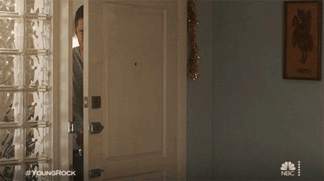 a man peeking out of a door with #youngrock on the bottom right