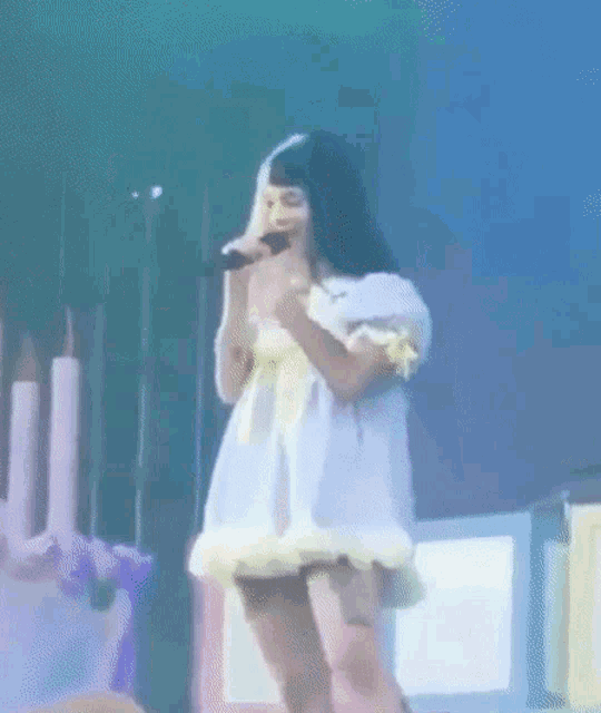 a woman in a white dress is singing into a microphone .