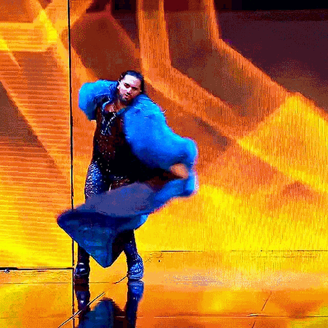 a woman wearing a blue fur coat is dancing on a stage
