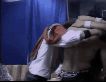 a group of people are hugging each other in a room with a blue curtain