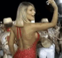 a woman in a red dress is dancing in front of a crowd at a carnival .